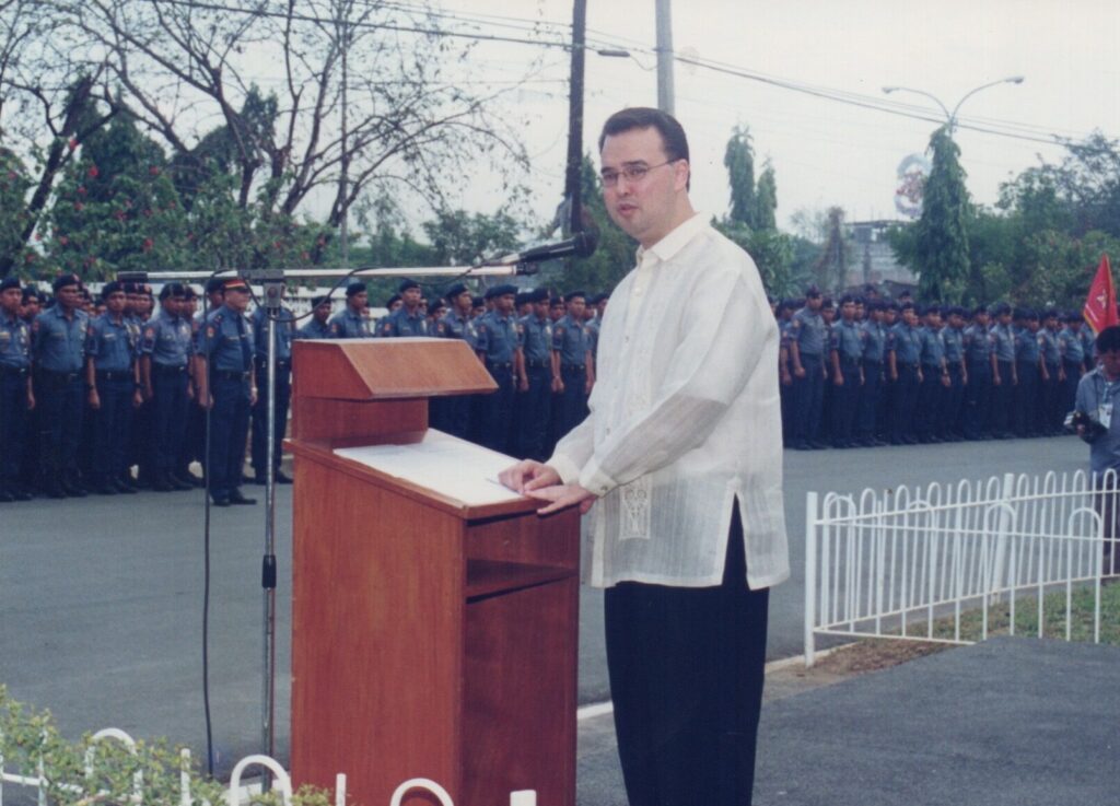 Alan Peter Cayetano delivers a speech before a uniformed police contingent, possibly during a formal event or ceremony.