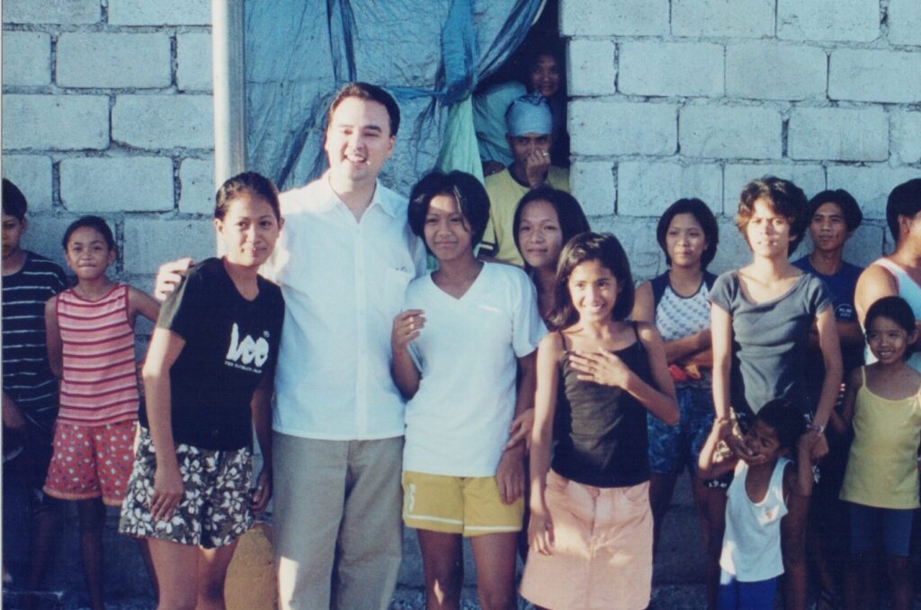 Alan Peter Cayetano smiles with community youth, fostering connections during a visit, highlighting engagement & approachable demeanor.
